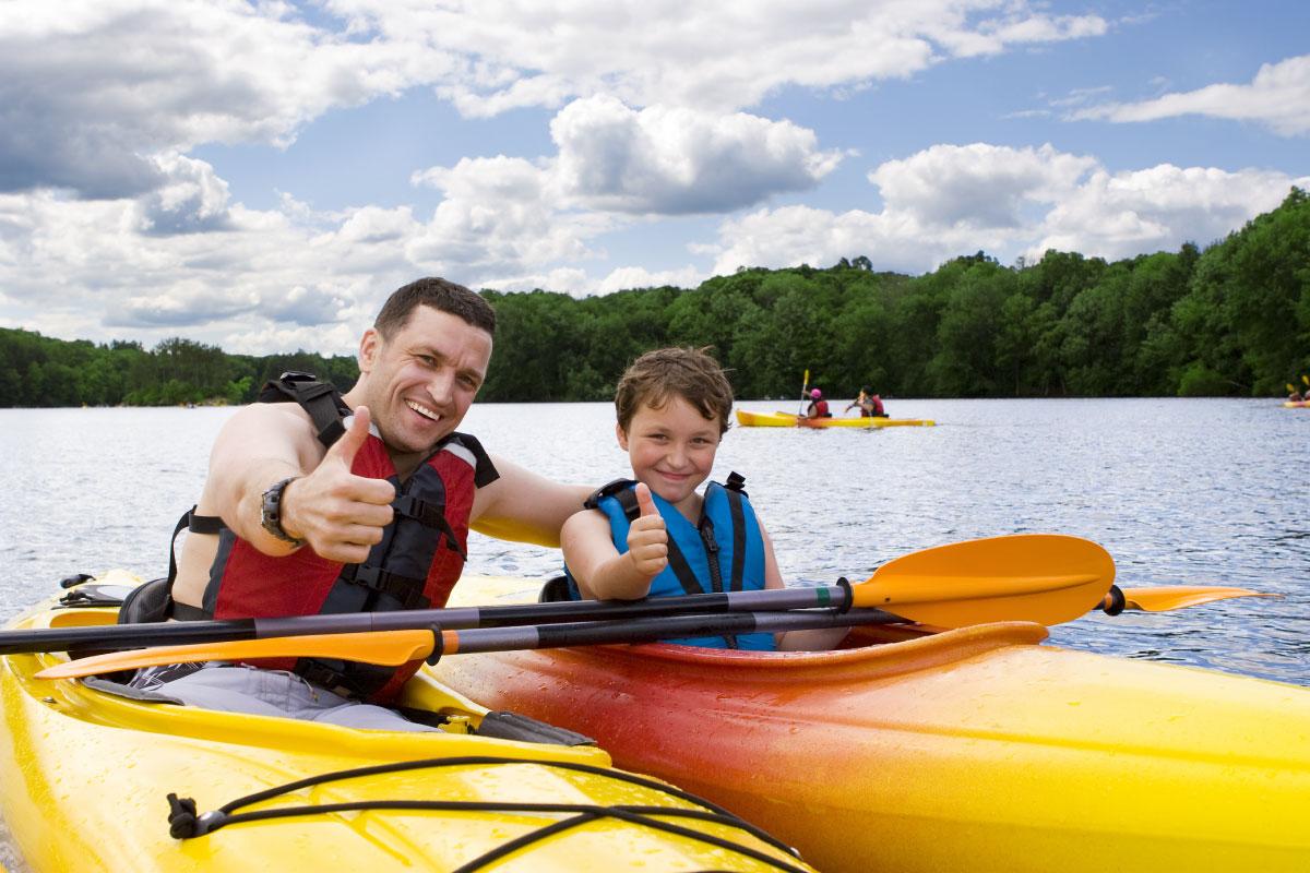 一个小男孩和父亲在水上划独木舟时竖起大拇指.